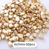 A pile of small, gold-colored heart-shaped acrylic beads for jewelry making