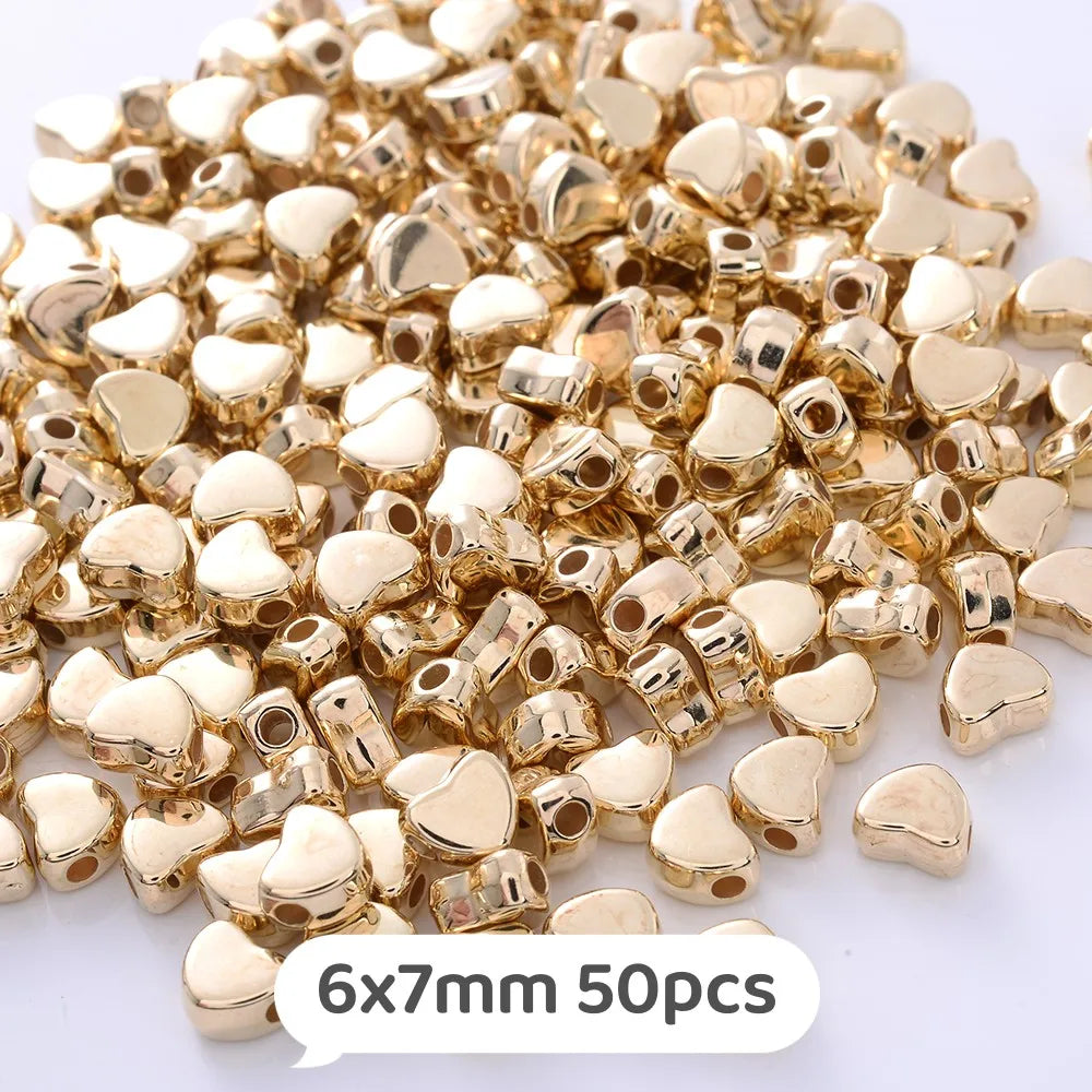 A pile of small, gold-colored heart-shaped acrylic beads for jewelry making
