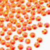 A close-up of small orange-red AB resin flatback rhinestones scattered on a white background.