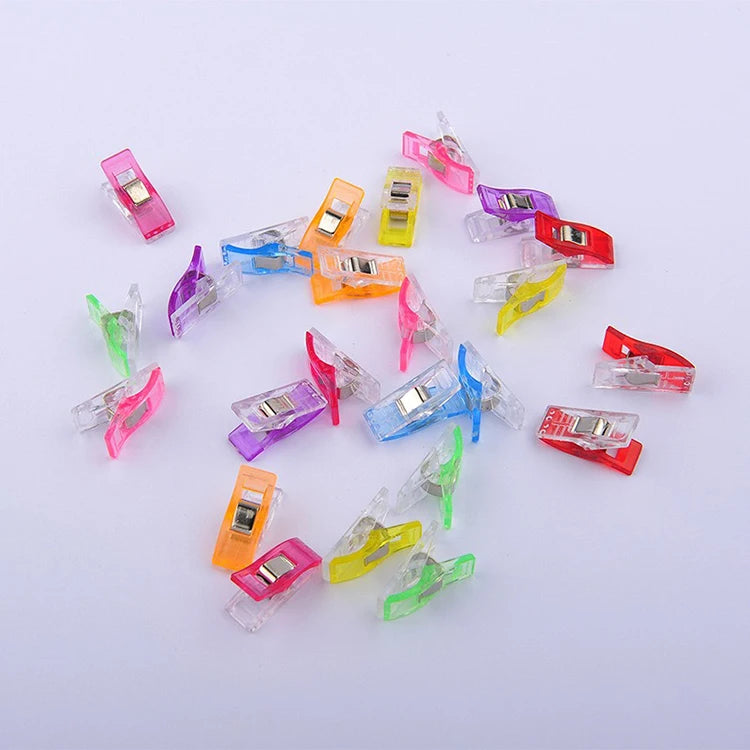 A collection of colorful plastic sewing clips in various shades including pink, yellow, purple, and red.