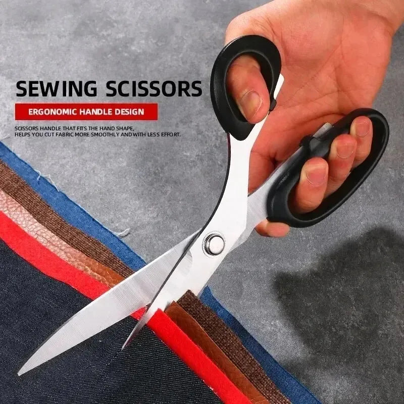 A hand holds a pair of black sewing scissors with an ergonomic handle design, positioned over fabric.