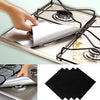 A hand is placing a reusable gas hob protector liner onto a stovetop grate.