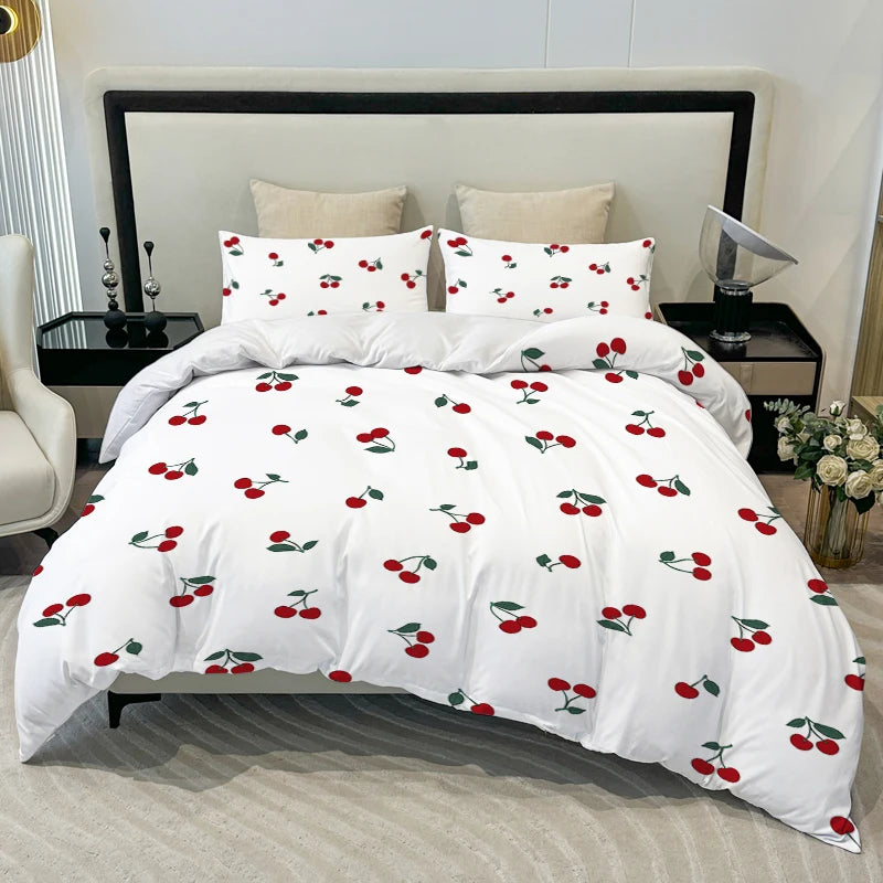 White duvet cover set with a red fruit print featuring cherries on a bed.