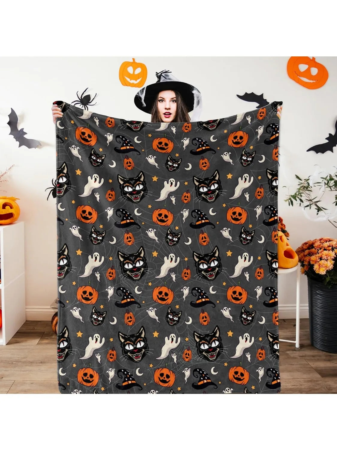 A dark gray flannel blanket featuring an all-over Halloween pattern with spiders, witches, and jack-o'-lanterns.