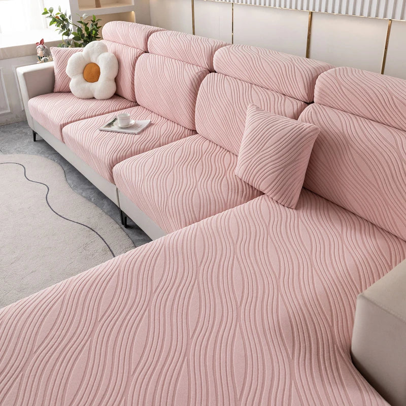 A pink plush elastic sofa cushion cover with a ribbed texture is displayed on a light-colored sofa.
