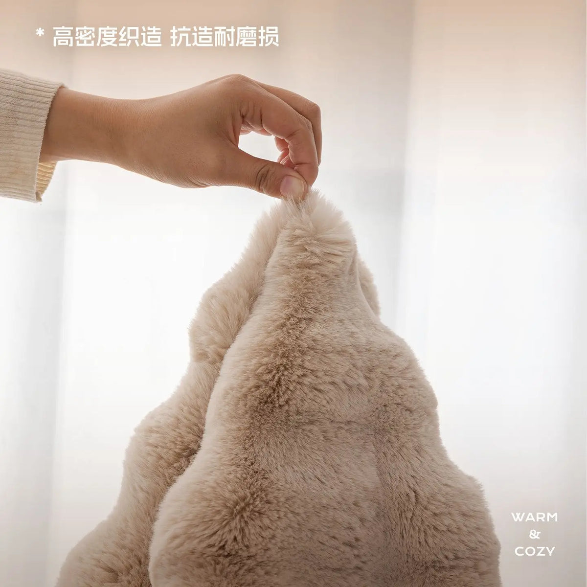 A hand is touching a fluffy, light beige rabbit fur sofa cushion cover.