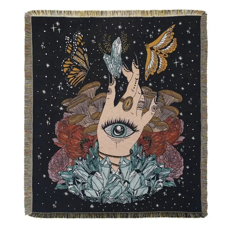 A dark throw blanket featuring a stylized hand with an eye surrounded by floral and geometric elements.