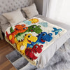 A colorful dinosaur cartoon throw blanket featuring various dinosaurs on a white bed.