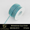 A spool of blue and teal rhinestone cup chain beads is shown with a loose strand extending from it.