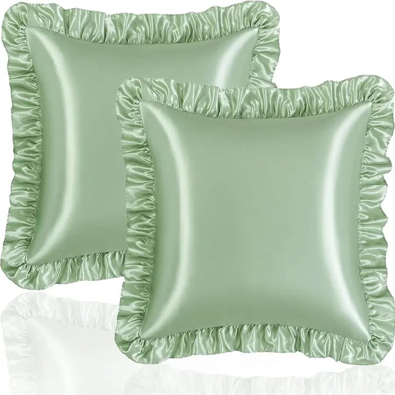 A set of two ruffled satin pillowcases in a sage green color.