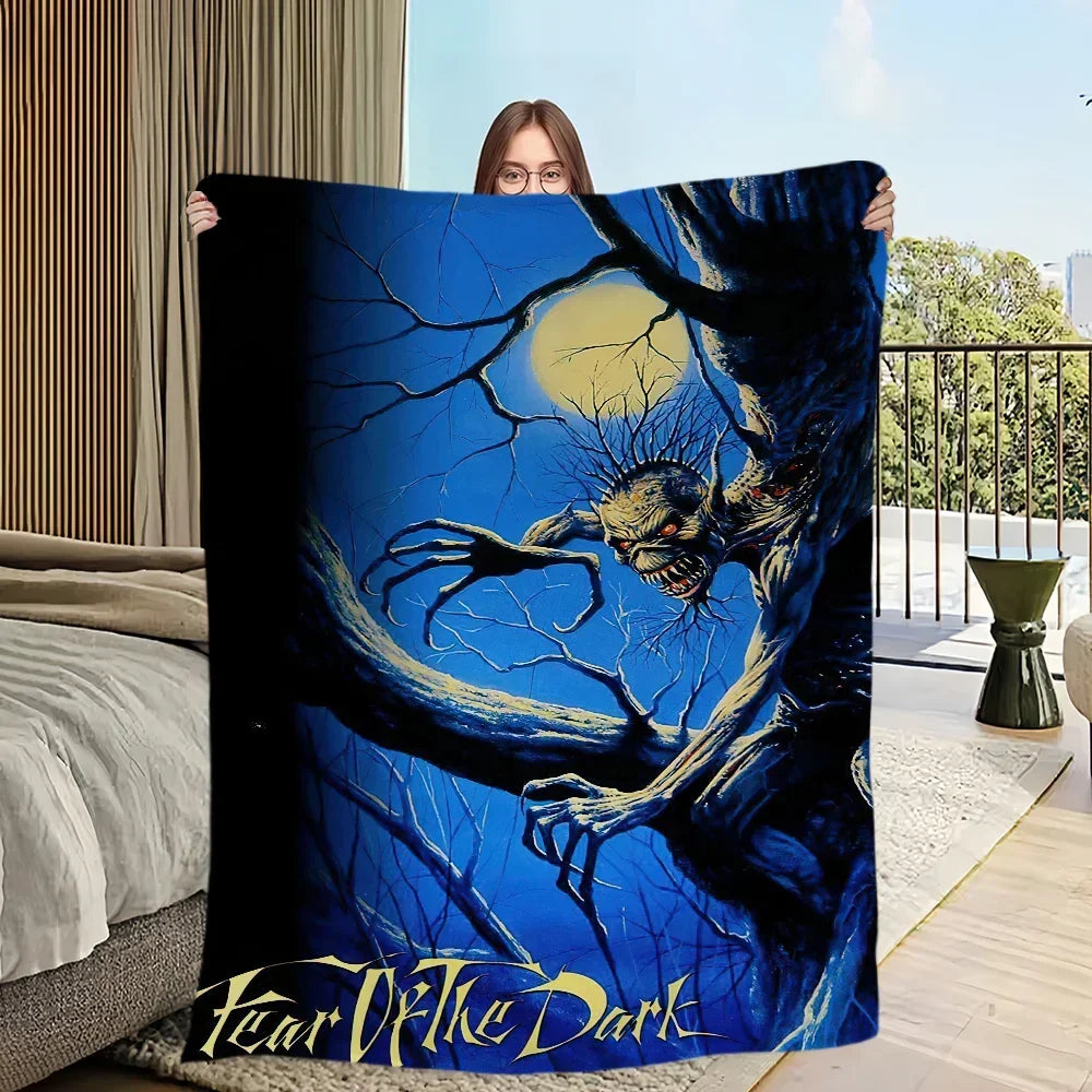A person holds up a dark blue and black graphic blanket featuring a menacing, skeletal hand against a bright blue background.