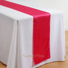 Elegant satin table runner in bright pink draped across a white tablecloth.