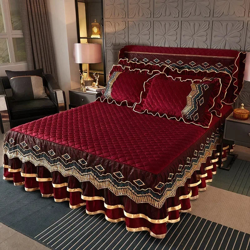 A deep red velvet bed skirt with gold embroidery and patterned fabric is displayed on a bed.