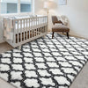 A geometric black and white faux fur area rug in a living room or bedroom setting.