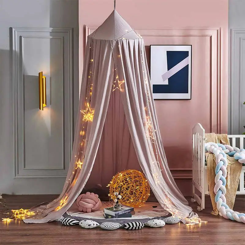 A pink princess hanging bed canopy with sheer fabric and fairy lights draped in a bedroom setting.