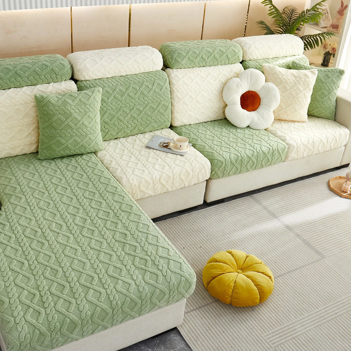 A light green plush velvet sofa cover with cream cushions and decorative pillows.