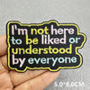 Black embroidered patch with white and light blue text saying I'm not here to be liked or understood by everyone