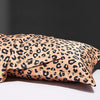 A close-up of leopard print silk satin pillowcases in a tan and black pattern resting on a white surface.