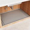 A silicone under sink cabinet liner installed in a wooden cabinet with a stainless steel faucet.