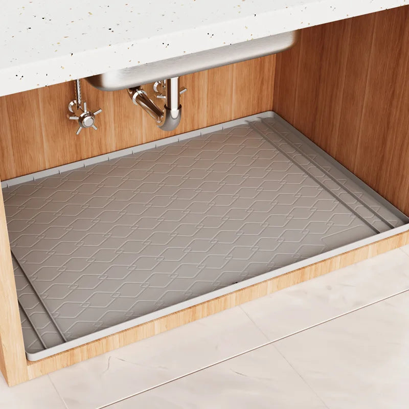 A silicone under sink cabinet liner installed in a wooden cabinet with a stainless steel faucet.