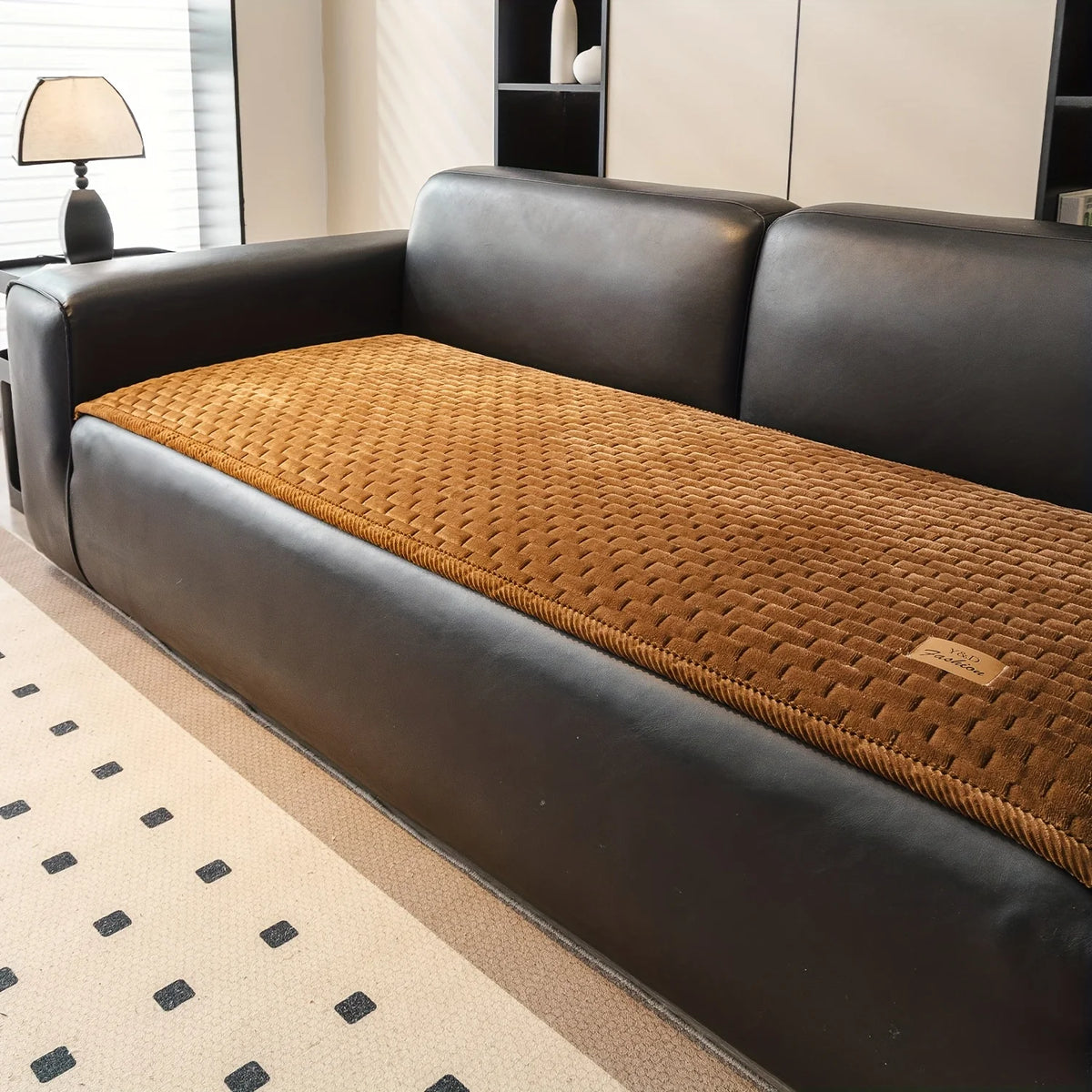 A dark brown leather sofa with a quilted tan cushion is shown in a modern living room setting.
