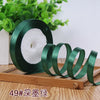 Roll of dark green satin ribbon used for crafting or decoration