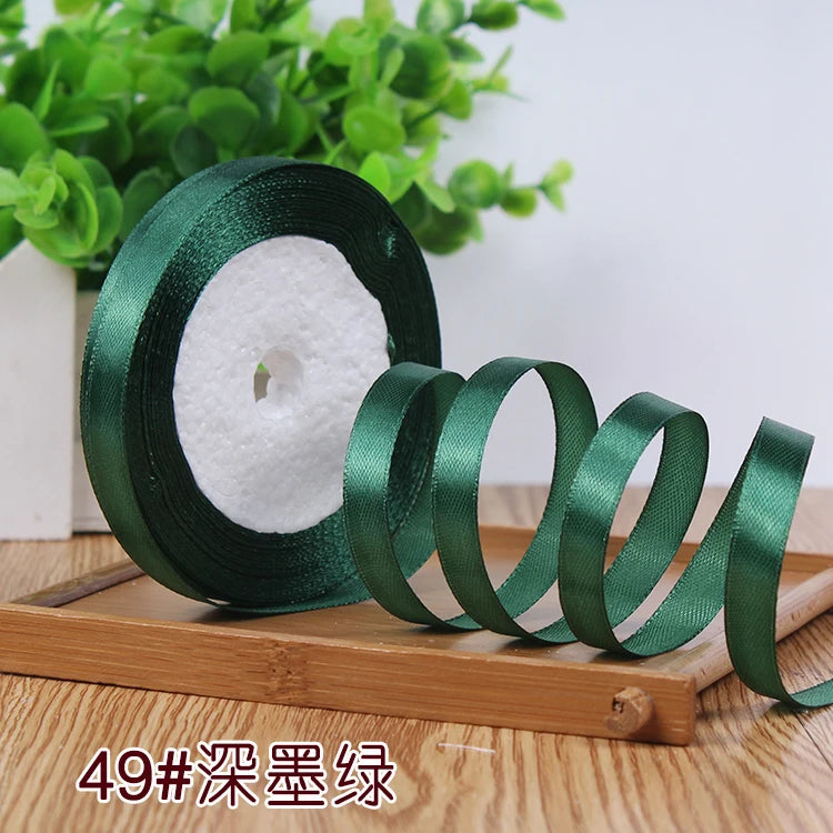 Roll of dark green satin ribbon used for crafting or decoration