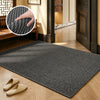 A rectangular black faux sisal runner rug placed on a light wood floor with a wooden bench and a dark door frame visible.