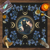 A dark mat featuring a central silhouette of a black cat surrounded by crescent moons and blue floral elements.