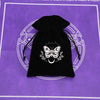 A black velvet tarot cards storage pouch with a white butterfly and crescent moon design, set against a purple background.