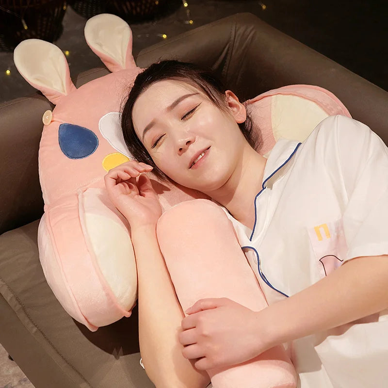 A person is resting their head on a pink plush animal sofa cushion indoors.