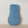 A light blue muslin cotton baby sleeping bag lying flat on a neutral surface.