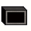 A stack of black solid linen blend table placemats with ornate gold-colored Greek key borders.