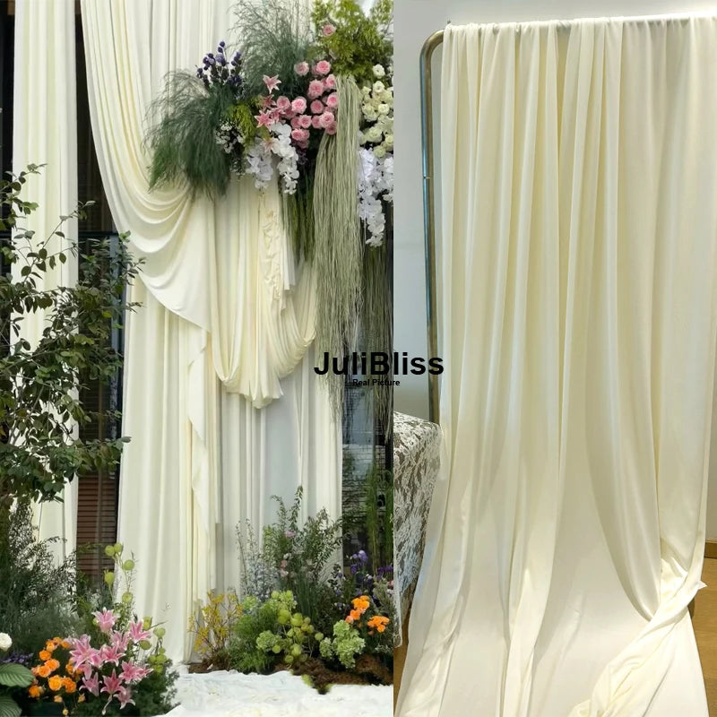 Cream sheer fabric draping used as a backdrop with floral greenery and white accents
