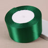 A roll of green satin ribbon with a white core used for crafting and decoration.