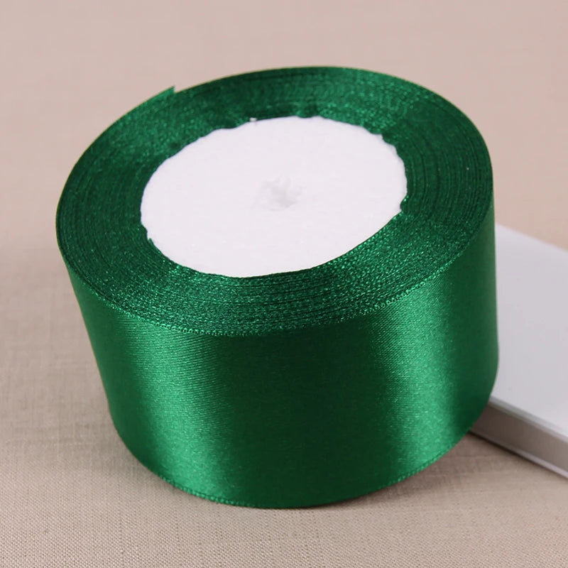 A roll of green satin ribbon with a white core used for crafting and decoration.