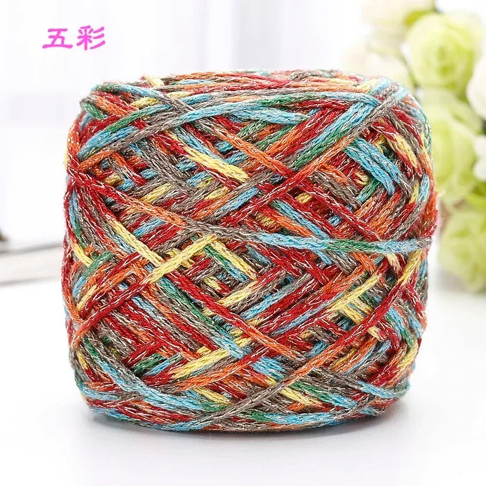A ball of multicolored metallic silk yarn with various shades of red, blue, yellow, and gray.