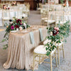 A gold sequin glitter tablecloth draped on a round table set for an elegant wedding or party.