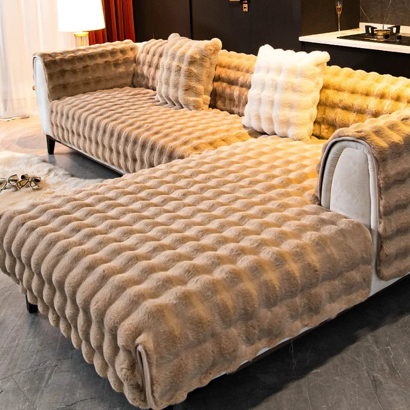 A plush velvet sofa cover with a textured, golden brown fabric and non-slip backing is displayed indoors.