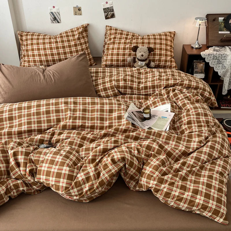 A brown and tan plaid duvet cover set with matching pillows and a decorative throw draped on a bed.