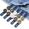 A set of adjustable button extenders for pants in various sizes and finishes, displayed on a denim jean fabric.