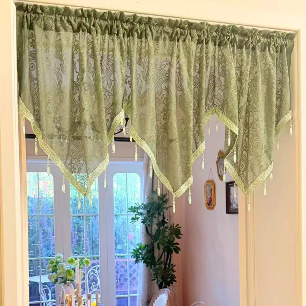 Elegant black lace curtain valance in sage green hangs over a window.