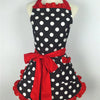 A black polka dot ruffle apron with red trim tied in a bow displayed on a mannequin.