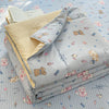 A stack of light gray cartoon quilting comforters with small animal patterns on a blue quilted surface.