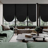 Interior view of a modern living room featuring black pleated blackout curtains and dark furniture.