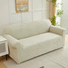 A beige sofa slipcover featuring a jacquard leaves pattern in off-white and cream tones.