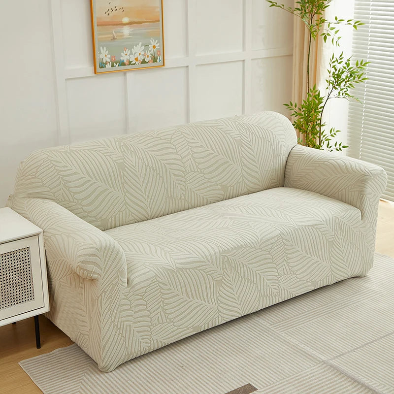 A beige sofa slipcover featuring a jacquard leaves pattern in off-white and cream tones.