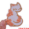 A white embroidered cartoon cat patch with peach colored floral accents.