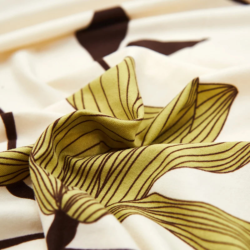 A close-up of stylish printed sofa protector covers featuring olive green stripes and dark brown leaf patterns on a white bac
