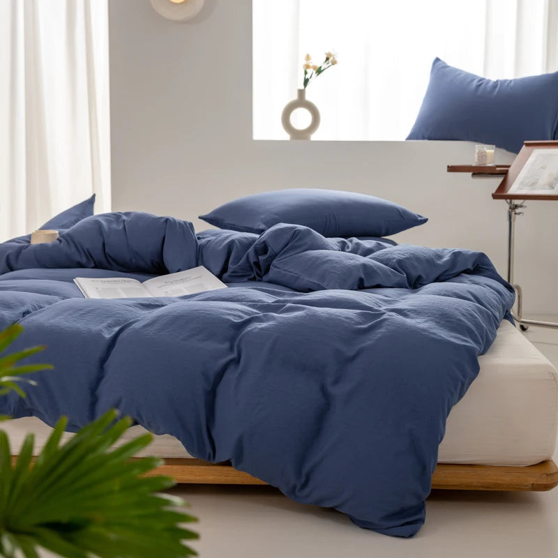 A navy blue minimalist duvet cover is displayed on a bed with white linens and natural wood framing.